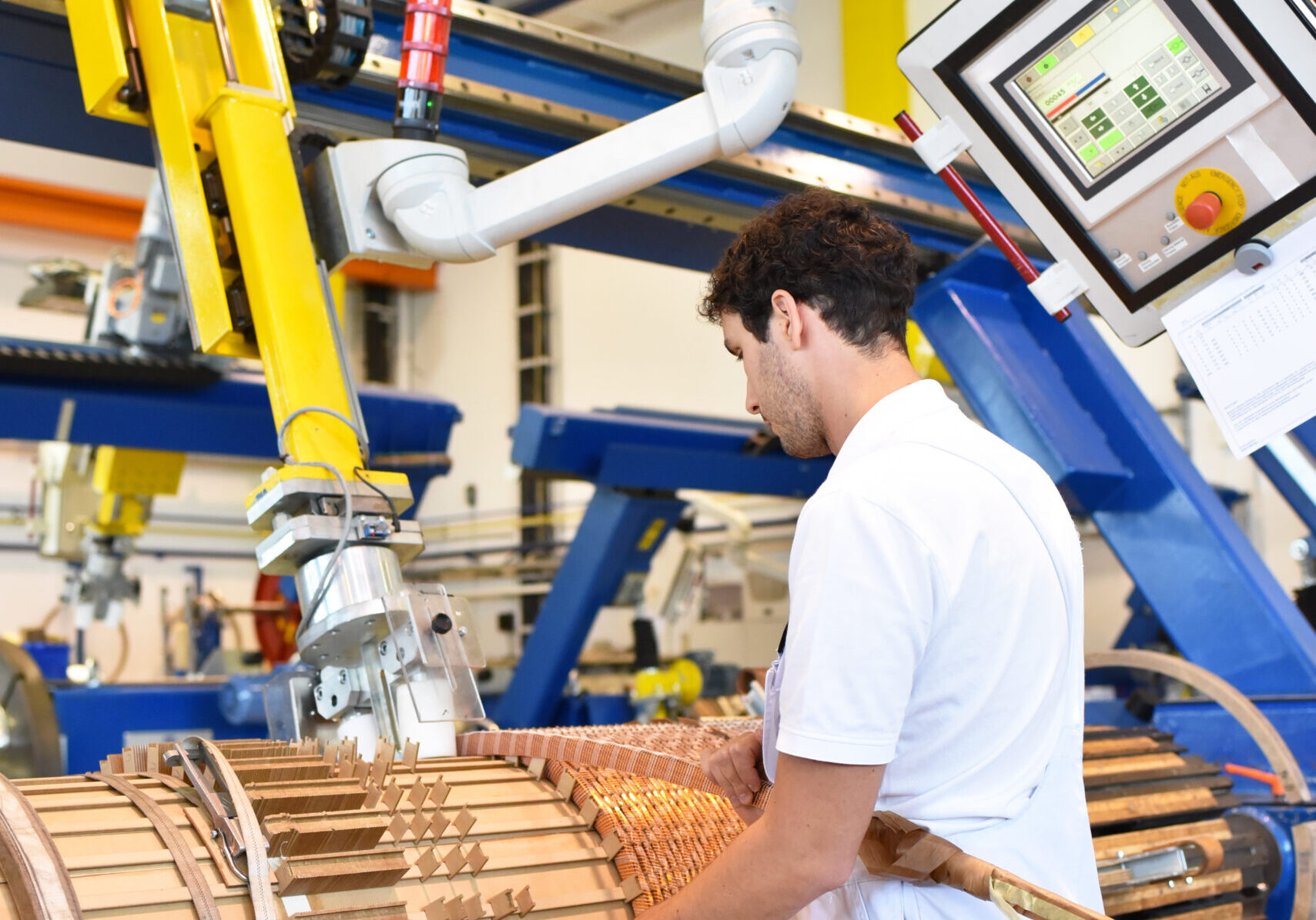 young mechanical engineering workers operate a machine for winding copper wire - manufacture of transformers in a factory